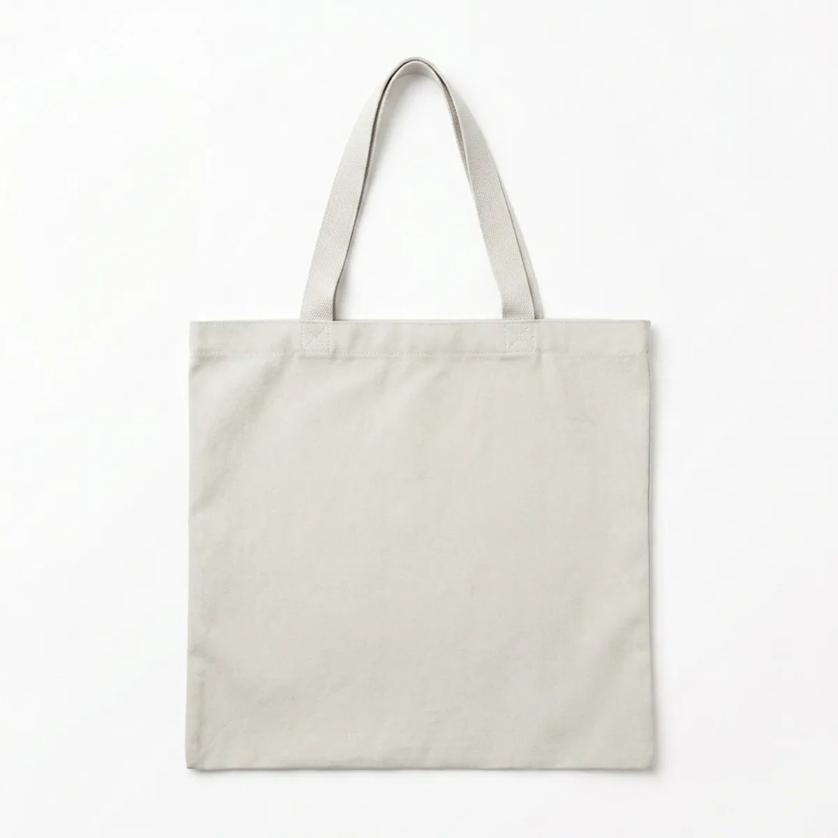 A plain cotton tote bag laid flat with its two handles laid open above it.