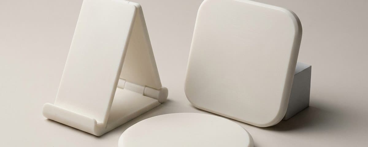 Three plain white design models of a charger stand and two pads, unfinished and unbranded.