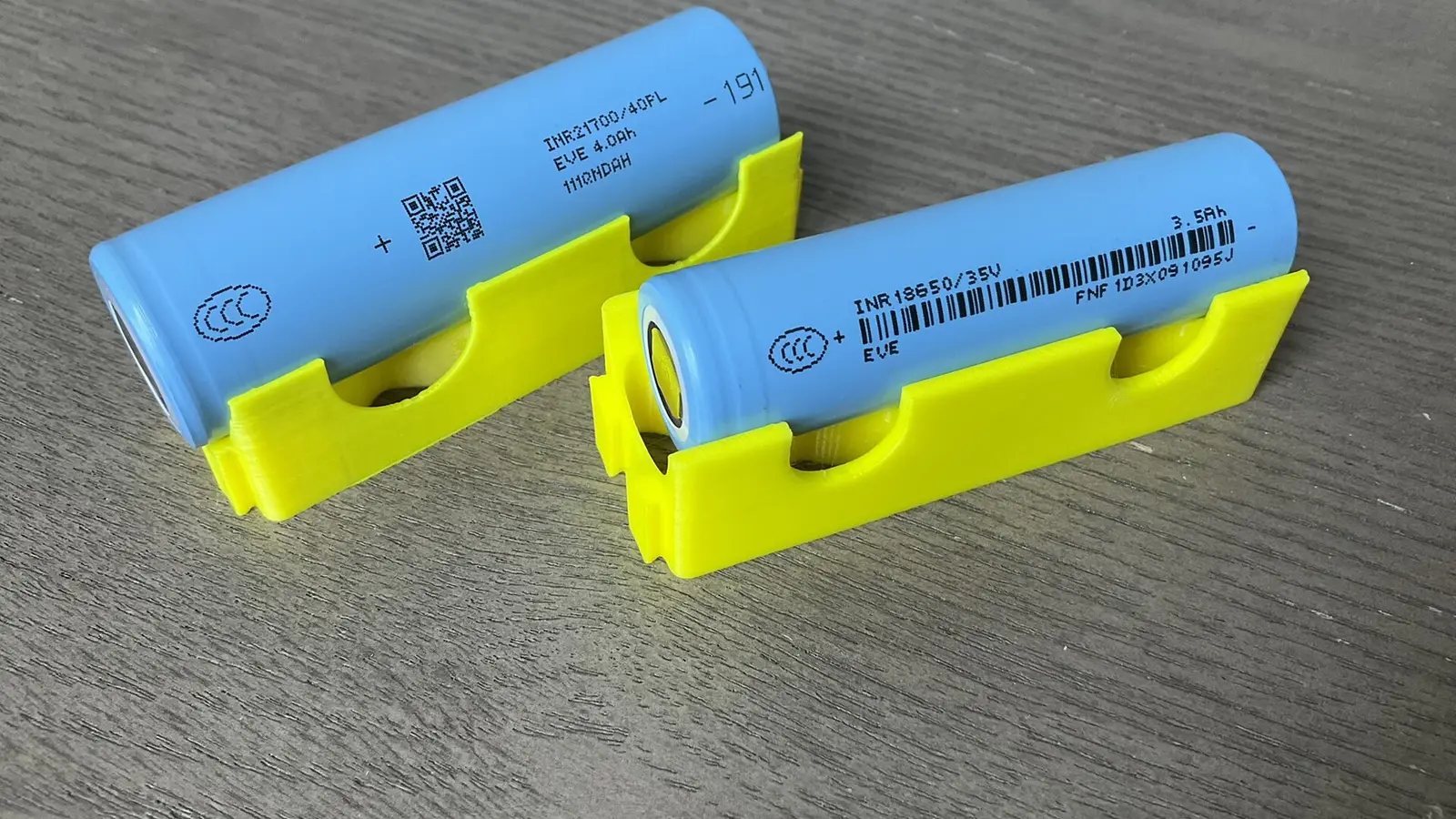 Two blue 18650 lithium-ion battery cells in yellow holders on a tabletop